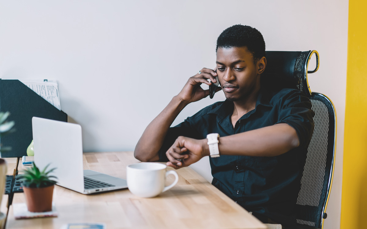 man checking his watch working at computer