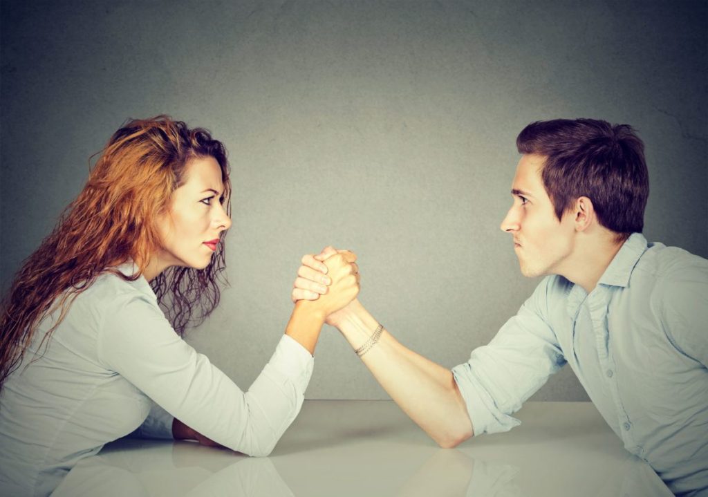 woman and man arm wrestling on table