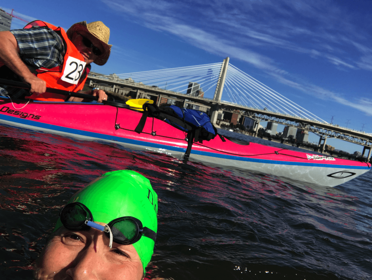 person in kayak following female swimmer in water