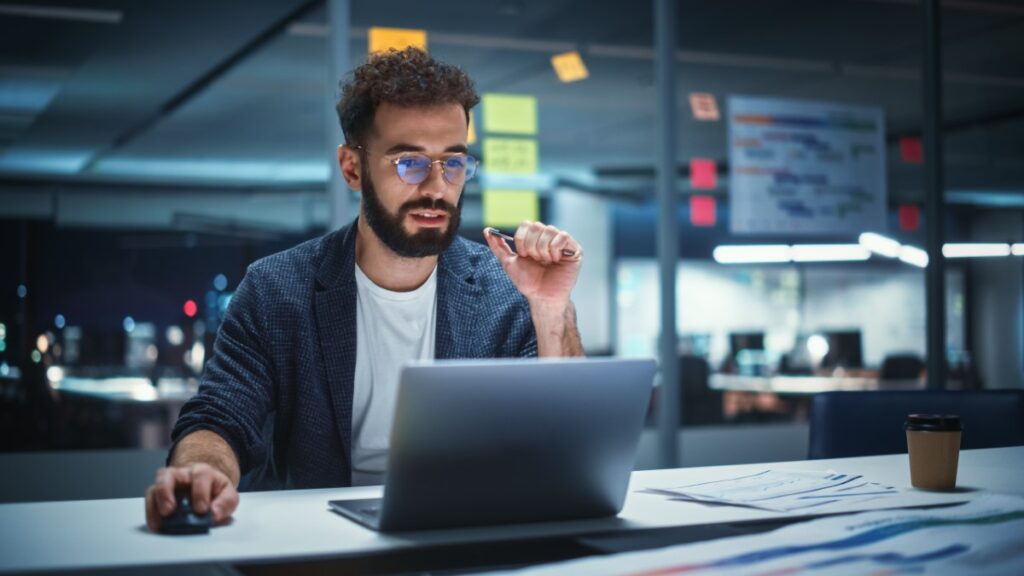 young male project developer looking at computer in office