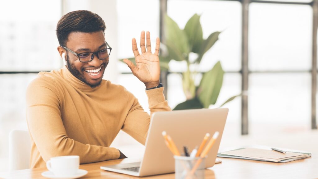 man smiling and waving at laptop