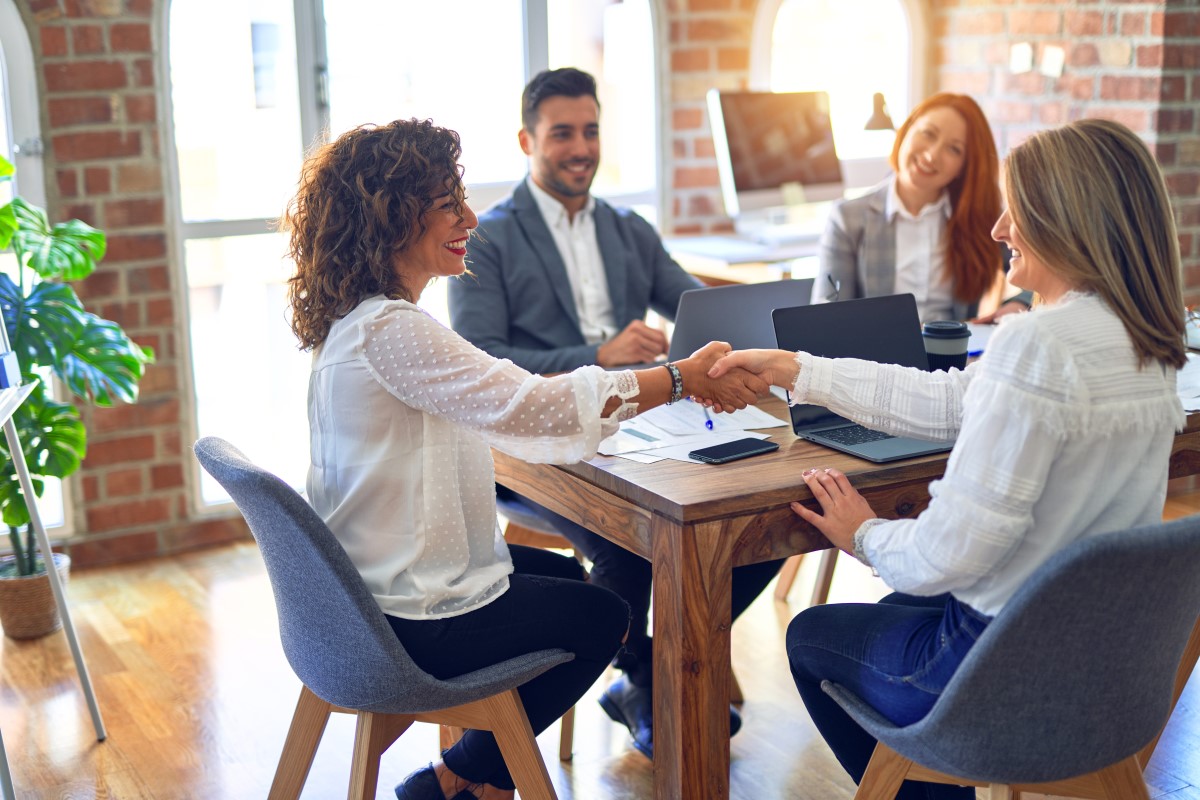 two employees shaking hands at business meeting