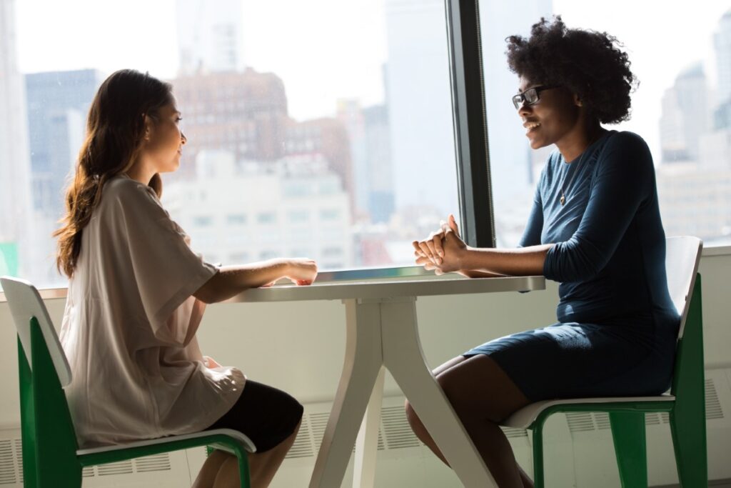 two women meeting in front of window