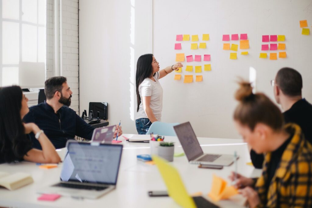 team member pointing at sticky notes on whiteboard