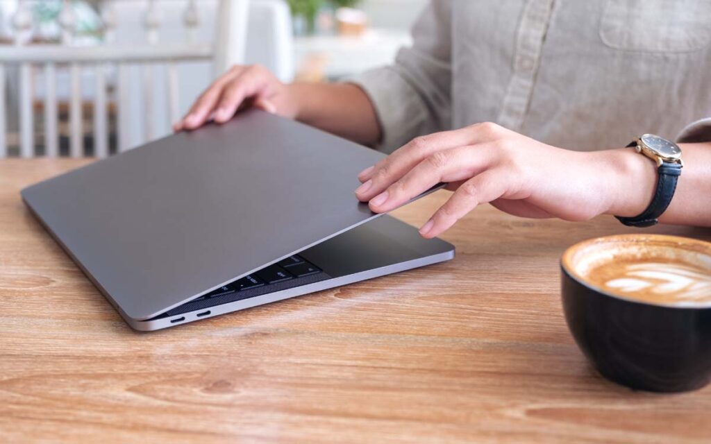 person closing a laptop in a cafe