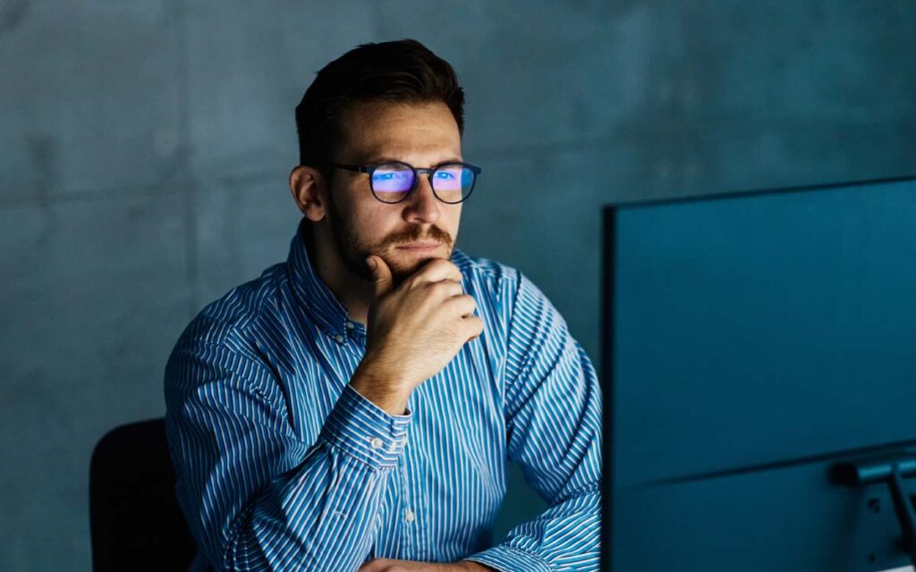 puzzled man looking at computer in dark office