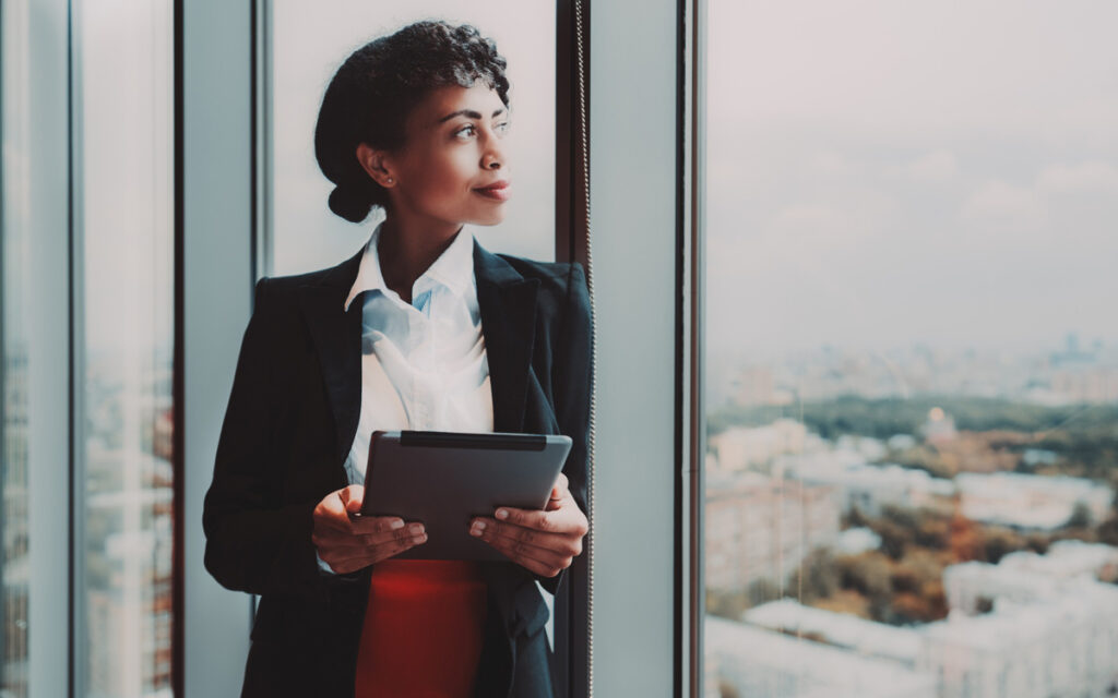 confident woman looking out large corporate office window